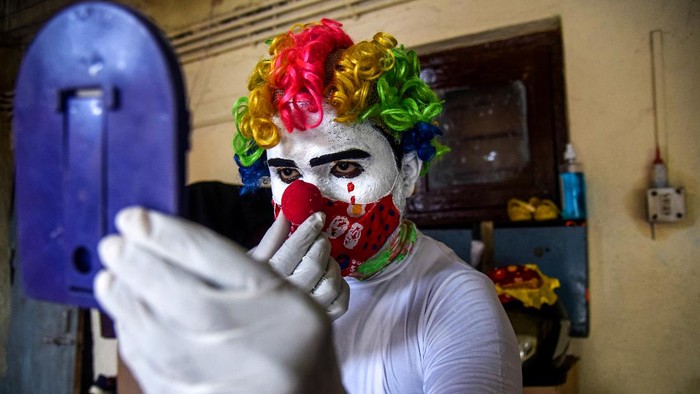 MUMBAI, INDIA - MAY 22: Ashok Jagannath Kurmi, a 36-year-old social worker, sprays disinfectant liquid while dressed in a clown costume at a slum on May 22, 2021 in Mumbai, India. Kurmi, 36, who works for a pharmaceutical company to earn money, says that he dresses in different costumes during his outreach to help spread official messages about the Covid-19 coronavirus to both children and adults. He says that dressing up in various ways, such as a clown, helps remind people to try and stay happy as well as healthy in the face of the unrelenting wave of infections that has swept India. India's prolonged and devastating wave of Covid-19 infections has gripped cities and overwhelmed health resources. (Photo by Fariha Farooqui/Getty Images)