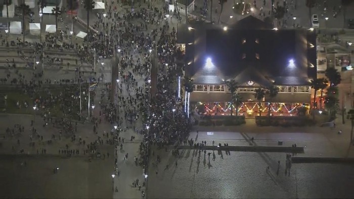 This Saturday, May 22, 2021 aerial screenshot provided by FOX 11 KTTV shows people gathered at the Huntington Beach pier in Huntington Beach, Calif. Police in Huntington Beach estimate that at least 1,000 people gathered by the fire pits on the sand Saturday night. A birthday party invitation that went viral on TikTok brought hundreds of people to a raucous celebration on a Southern California beach, prompting police to declare an unlawful assembly and arrest about 150 people after they refused orders to disperse. (Fox 11 KTTV via AP)