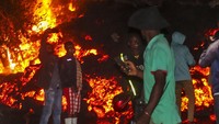 Orang-orang berdiri dan berfoto selfie di depan lahar dari letusan Gunung Nyiragongo di Buhene, pinggiran Goma, Kongo, Minggu (23/5/2021), dini hari waktu setempat. (AP Photo/Justin Kabumba)  