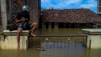 Seorang warga menaiki pagar rumahnya saat banjir melanda Kampung Bojongasih, Dayeuhkolot, Kabupaten Bandung, Jawa Barat, Selasa (25/5/2021).
