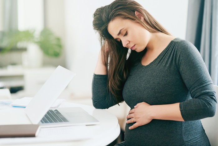 hamil Shot of a young pregnant woman feeling unwell while working from home