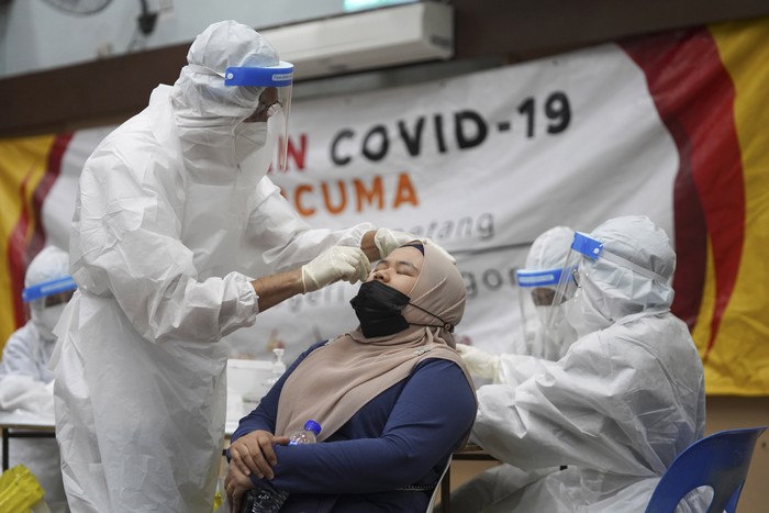 A medical worker collects a swab sample from a woman during coronavirus testing at a COVID-19 testing center in Ulu Klang, on the outskirts of Kuala Lumpur, Malaysia, Tuesday, May 18, 2021. (AP Photo/Vincent Thian)
