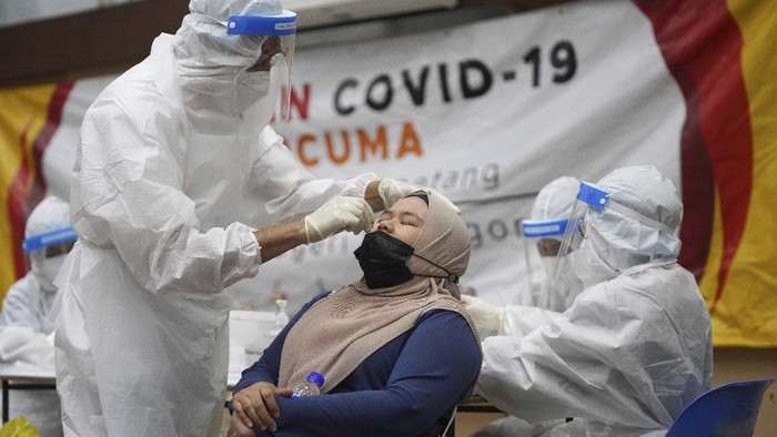 A medical worker collects a swab sample from a woman during coronavirus testing at a COVID-19 testing center in Ulu Klang, on the outskirts of Kuala Lumpur, Malaysia, Tuesday, May 18, 2021. (AP Photo/Vincent Thian)