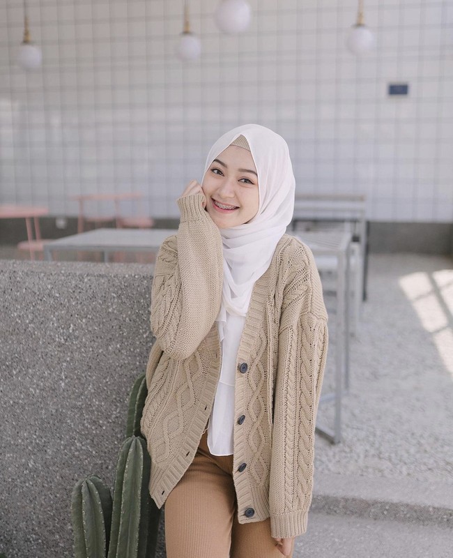 Sari Endah Pratiwi memakai hijab pashmina putih yang dibentuk menutupi bagian dada. Ia memadukan dengan cardigan rajut warna nude. Bawahanya ia memakai celana warna cokelat. Foto: Dok. Instagram @saritiw.