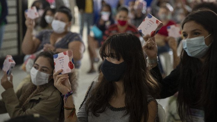 Wanita Brasil Dapat Sumbangan Pembalut Kala Pandemi Women and girls sit after receiving a donation of sanitary napkins and other female hygiene supplies provided by the local NGO