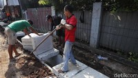 Tampak para pekerja menutup saluran air yang telah selesai dikerjakan.