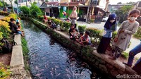 Sejumlah warga mendatangi saluran air di Kompleks Puri Pamulang, Tangerang Selatan, yang kini dipenuhi ikan hias, Kamis (27/5/2021).