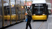 Seorang pejalan kaki berjalan di antara dua trem di Alexanderplatz di Berlin, Jerman. Getty Images/Adam Berry  
