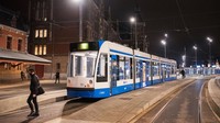 Orang-orang berjalan melewati trem di Amsterdam Central di Amsterdam, Belanda. Getty Images/Sabine van Wechem  