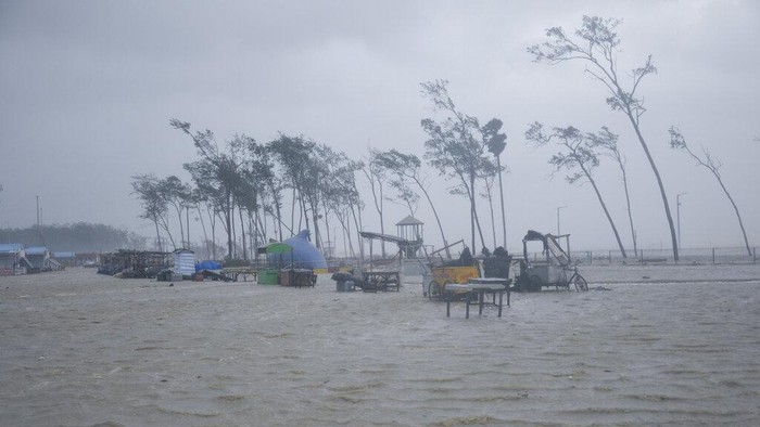A villager walks holding an umbrella as dark clouds loom over during a drizzle in Balasore district in Odisha, India, Tuesday, May 25, 2021. Tens of thousands of people were evacuated Tuesday in low-lying areas of two Indian states and moved to cyclone shelters to escape a powerful storm barreling toward the eastern coast. (AP Photo)