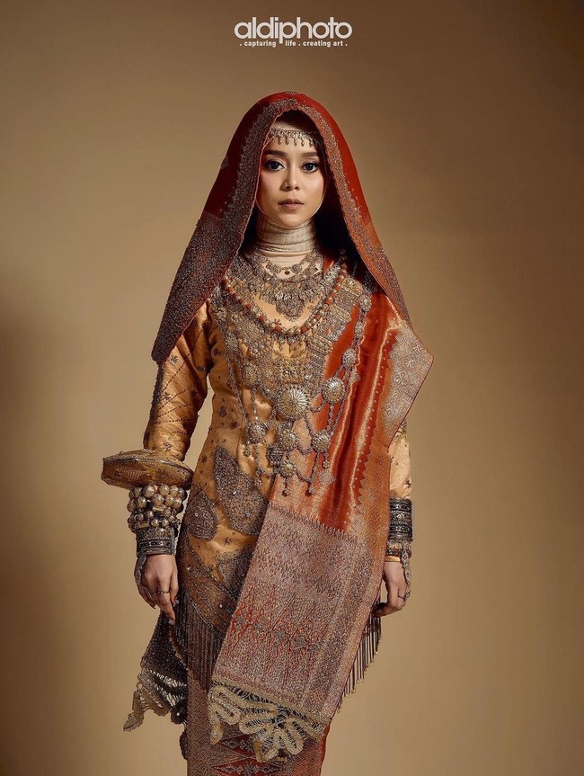 Lesti Kejora dan Rizky Billar beberapa waktu lalu terlihat membagikan foto-foto prewedding keduanya. Lesti tampak cantik mengenakan busana Koto Gadang berwarna merah dan gold. Penampilannya itu dilengkapi dengan beragam aksesori seperti gelang dan kalung. Foto: Instagram/aldiphoto