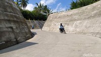 Pengendara sepeda motor melintas di jalan berkelok yang menuju sabo dam.