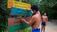Warga suku Pataxo Ha-ha-hae memperbaiki rambu-rambu di pintu masuk pantai Irirí di Paraty, Brasil.  