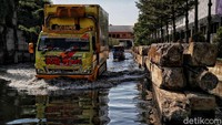 Pekerja harus menerobos genangan banjir menuju pabrik ikan.