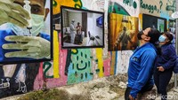 Warga melihat foto-foto tentang COVID-19 yang dipemerkan.