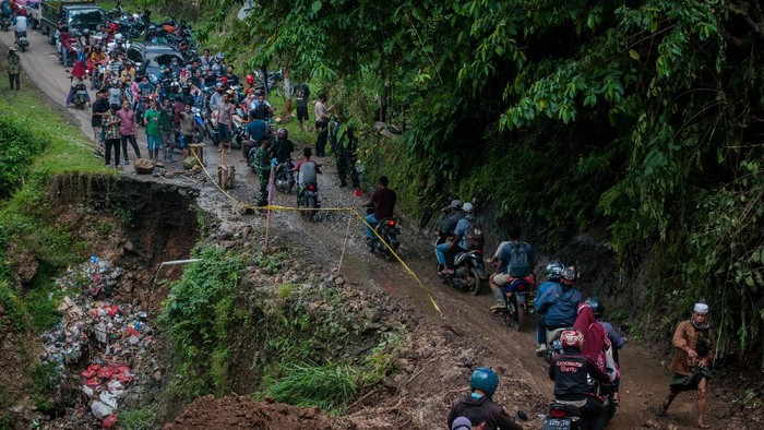 Sejumlah pengendara melintas di jalan yang longsor di Kecamatan Lebakgedong, Lebak, Banten, Minggu (30/5/2021). Badan Penanggulangan Bencana Daerah (BPBD) Kabupaten Lebak mengatakan akses jalan sepanjang 50 meter penghubung antar Provinsi Banten-Jawa Barat tersebut longsor akibat hujan dengan intensitas tinggi yang terjadi pada Sabtu (29/5/2021). ANTARA FOTO/Muhammad Bagus Khoirunas/wsj.