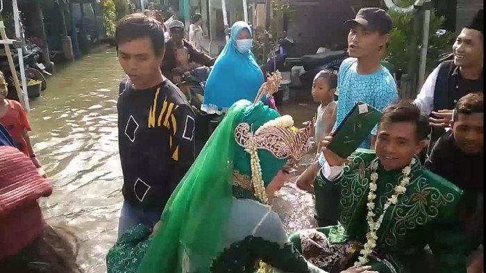 Pengantin menerjang banjir rob di Demak, Minggu (30/5/2021).