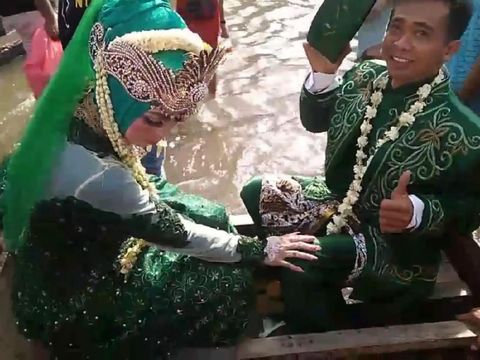 Pengantin menerjang banjir rob di Demak, Minggu (30/5/2021).