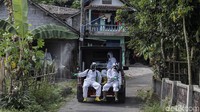 Petugas dengan mobil terbuka menyemprot seluruh jalan-jalan di desa tersebut.