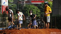 Seorang pria bersama anaknya menikmati lintasan sepeda pump track.