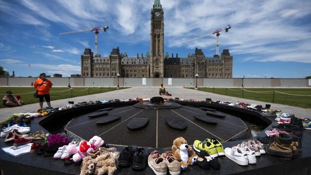 Shoes line the edge of the Centennial Flame on Parliament Hill in memory of the 215 children whose remains were found at the grounds of the former Kamloops Indian Residential School at Tk'emlups te Secwépemc First Nation in Kamloops, British Columbia, on Sunday, May 30, 2021, (Justin Tang/The Canadian Press via AP)