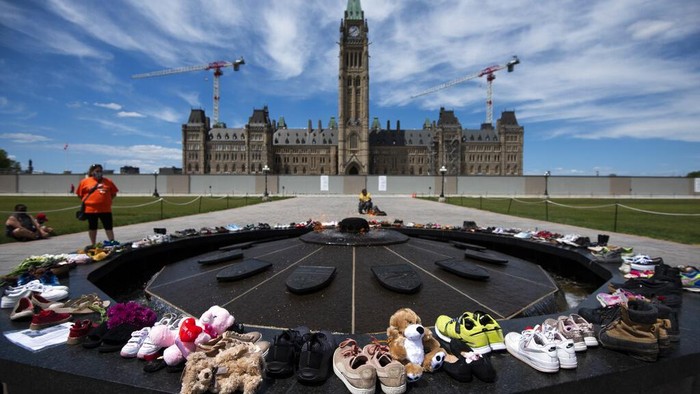 Aksi Mengenang 215 Jasad Anak-anak Kanada yang Ditemukan di Bekas Sekolah Shoes line the edge of the Centennial Flame on Parliament Hill in memory of the 215 children whose remains were found at the grounds of the former Kamloops Indian Residential School at Tk'emlups te Secwépemc First Nation in Kamloops, British Columbia, on Sunday, May 30, 2021, (Justin Tang/The Canadian Press via AP)