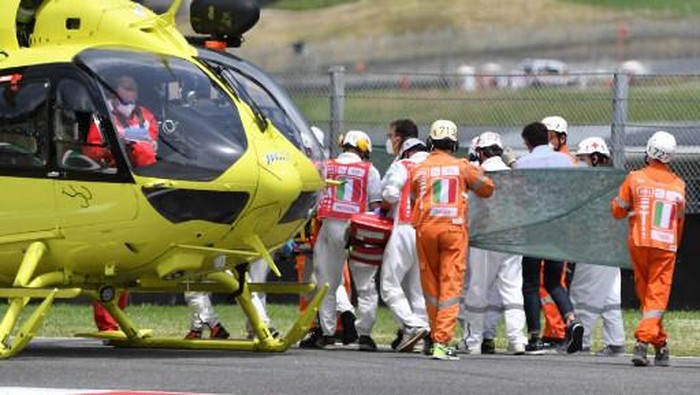 Medical officers clear the track as they evacuate Swiss Moto3 rider Jason Dupasquier in an helicopter after a crash during a qualifying session ahead the Italian Moto GP Grand Prix at the Mugello race track in Scarperia e San Piero on May 29, 2021. - Swiss Moto3 rider Jason Dupasquier was being taken to hospital after a three-bike crash that halted qualifying for the Italian motorcycling Grand Prix at Mugello on May 29, 2021. Organisers said the stricken teenager was being taken to hospital in Florence to undergo tests. Japanese rider Ayumu Sasaki and Spaniard Jeremy Alcoba were the others involved in the accident which delayed the MotoGP fourth practice with organisers reporting both were fine. (Photo by Tiziana FABI / AFP)
