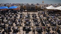 Seorang penyanyi tampil saat orang makan dan minum di meja yang disediakan di Pantai Brighton.  