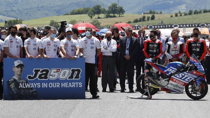 Teammates of 19 years-old Swiss pilot Jason Dupasquier stand near his motorbike, right, as they pay a minute of silence in his memory prior to the start of the Motogp Grand Prix of Italy at the Mugello circuit, in Scarperia, Italy, Sunday, May 30, 2021. Dupasquier died Sunday after being hospitalized Saturday, at the Florence hospital following his crash during the qualifying practices of the Moto3. (AP Photo/Antonio Calanni)