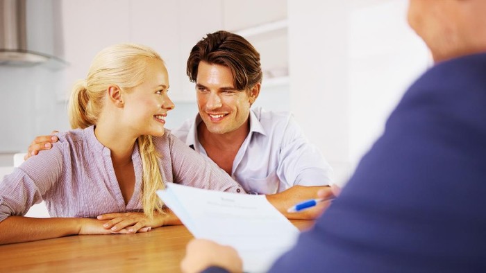 A young couple discussing their future at a table with their consultant