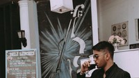 Dengan mengenakan pakaian serba hitam, Bryan tampak terlihat keren saat pse menyeruput minuman di sebuah kafe kekinian. Foto: Instagram @bryanmckenziee