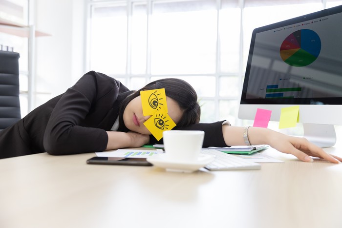 pekerja kantoran Asian businesswoman in black suit tired frustrated from working at the computer screen. She covering eyes, fake eyes with note pad and Sleeping in desk at office building.
