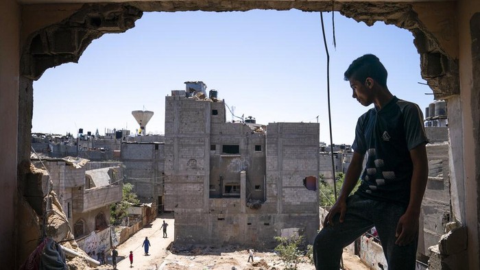 Mahmoud Al-Masri, 14, stands for a portrait in his bedroom that was damaged when an airstrike destroyed the neighboring building prior to a cease-fire that halted an 11-day war between Gazas Hamas rulers and Israel, Wednesday, May 26, 2021, in Beit Hanoun, Gaza Strip. (AP Photo/John Minchillo)