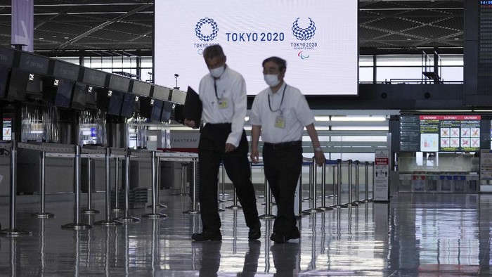 A man wearing a protective mask to help curb the spread of the coronavirus pauses near a banner of Tokyo 2020 Olympic at Narita International Airport Tuesday afternoon, June 1, 2021, in Narita, east of Tokyo. A state of emergency in Tokyo, Osaka and other prefectures was last week extended until June 20 as COVID-19 cases continue to put the medical system under strain.(AP Photo/Eugene Hoshiko)