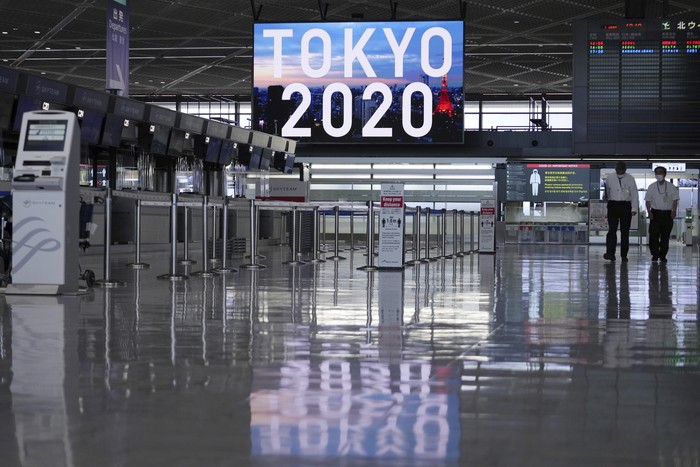 A man wearing a protective mask to help curb the spread of the coronavirus pauses near a banner of Tokyo 2020 Olympic at Narita International Airport Tuesday afternoon, June 1, 2021, in Narita, east of Tokyo. A state of emergency in Tokyo, Osaka and other prefectures was last week extended until June 20 as COVID-19 cases continue to put the medical system under strain.(AP Photo/Eugene Hoshiko)