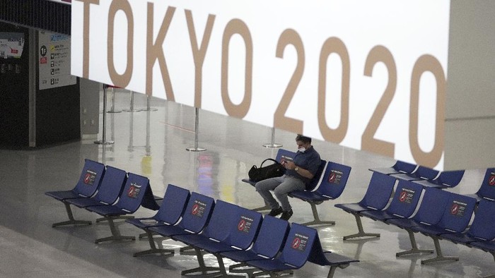 A man wearing a protective mask to help curb the spread of the coronavirus pauses near a banner of Tokyo 2020 Olympic at Narita International Airport Tuesday afternoon, June 1, 2021, in Narita, east of Tokyo. A state of emergency in Tokyo, Osaka and other prefectures was last week extended until June 20 as COVID-19 cases continue to put the medical system under strain.(AP Photo/Eugene Hoshiko)