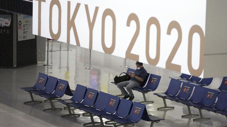 A man wearing a protective mask to help curb the spread of the coronavirus pauses near a banner of Tokyo 2020 Olympic at Narita International Airport Tuesday afternoon, June 1, 2021, in Narita, east of Tokyo. A state of emergency in Tokyo, Osaka and other prefectures was last week extended until June 20 as COVID-19 cases continue to put the medical system under strain.(AP Photo/Eugene Hoshiko)