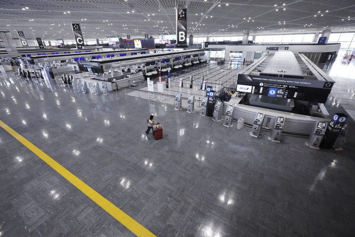 A man wearing a protective mask to help curb the spread of the coronavirus pauses near a banner of Tokyo 2020 Olympic at Narita International Airport Tuesday afternoon, June 1, 2021, in Narita, east of Tokyo. A state of emergency in Tokyo, Osaka and other prefectures was last week extended until June 20 as COVID-19 cases continue to put the medical system under strain.(AP Photo/Eugene Hoshiko)