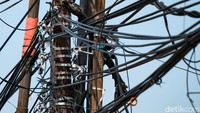 Kabel-kabel tampak semrawut di atas tiang.