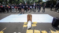 Dalam aksinya, mereka membawa batu nisan, bendera kuning dan kain dibentuk seperti jenazah.
