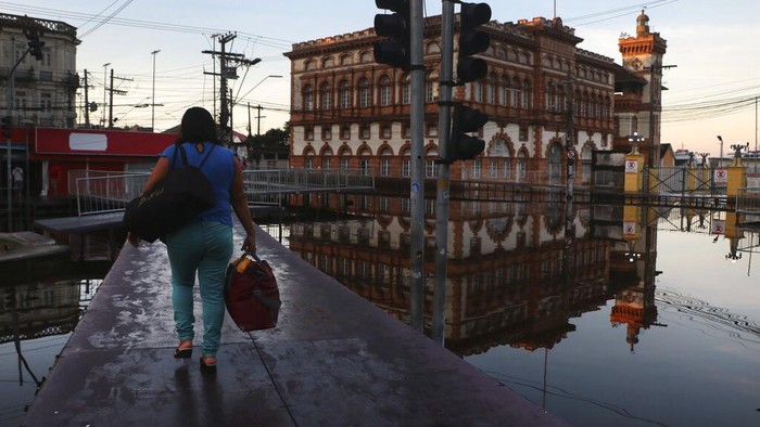 Gegara Banjir, Brasil Berubah Bak Kota Apung A man tries to open the door of his house, flooded by the waters of the Negro River in Manaus, Amazonas state, Brazil, Tuesday, June 1, 2021. Rivers around Brazil's biggest city in the Amazon rain forest have swelled to levels unseen in over a century of record-keeping, according to data published Tuesday by Manaus' port authorities. (AP Photo/Edmar Barros)
