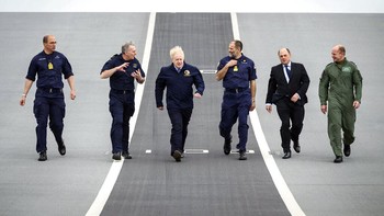 Sebelum keberangkatan HMS Queen Elizabeth, Perdana Menteri Inggris Boris Johnson melakukan kunjungan. Tampak ia berada di geladak kapal yang cukup luas bersama para petinggi militer Inggris. Foto: Associated Press
