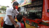 Petugas mengawasi dan membantu anak-anak mengakses internet.