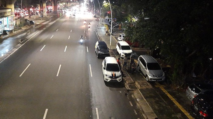 Mobil parkir di trotoar depan Halte TransJakarta Kayu Putih Rawasari, Jakarta Pusat saat malam hari.