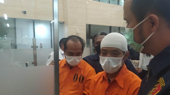Pelaku Obligasi Dragon inisial AM mengenakan peci putih dan JM di Bareskrim Polri, Jakarta, Rabu (2/6/2021).