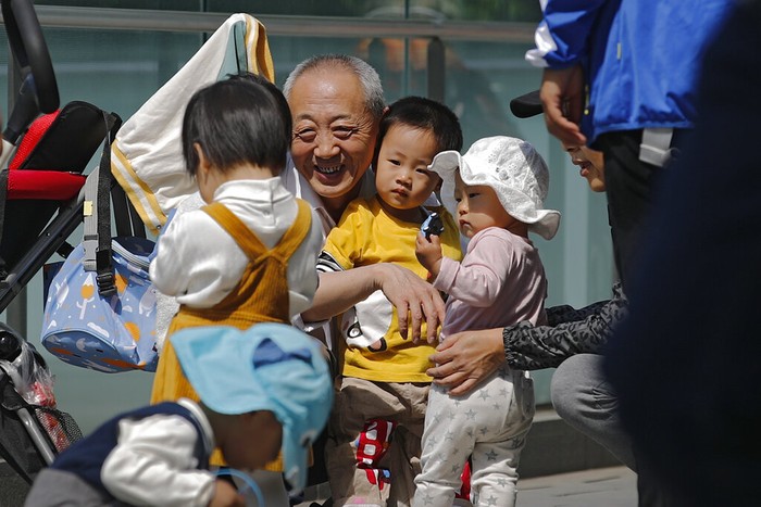 A woman plays with a child in a compound near a commercial office building in Beijing on May 10, 2021. Chinas ruling Communist Party will ease birth limits to allow all couples to have three children instead of two to cope with the rapid rise in the average age of its population, a state news agency said Monday. (AP Photo/Andy Wong)