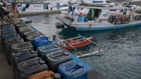 Pekerja menurunkan BBM jenis solar ke kapal nelayan di Pelabuhan Pendaratan Ikan (PPI) Donggala, Sulawesi Tengah, Selasa (1/6/2021).