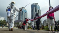 Guna mengantisipasi penyebaran virus Corona, petugas tampak menyemprotkan cairan disinfektan di sekitar massa yang hendak membentangkan bendera Merah Putih berukuran raksasa.  