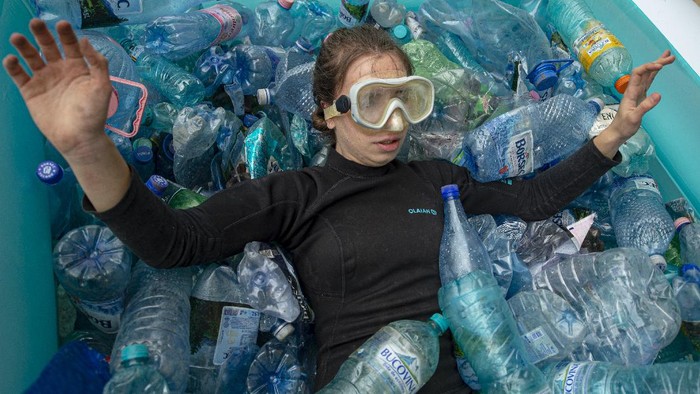 Aksi Aktivis Rumania Kala Protes Lingkungan An activist lies in an inflatable pool filled with PET plastic bottles during a protest outside the environment ministry demanding the introduction of the deposit refund scheme that will stimulate the population to recycle in Bucharest, Romania, Thursday, June 3, 2021. Romania has the second lowest rate of recycling in the European Union with just 11 percent of the waste being recycled, compared to the block's average of 47 percent. (AP Photo/Alexandru Dobre)