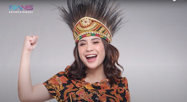 Nagita Slavina tampak cantik mengenakan baju adat Papua yang telah dimodifikasi. Lengkap dengan ikat kepala rumbai khas Papua, penampilan Nagita semakin mempesona. Foto: YouTube/Rans Entertainment